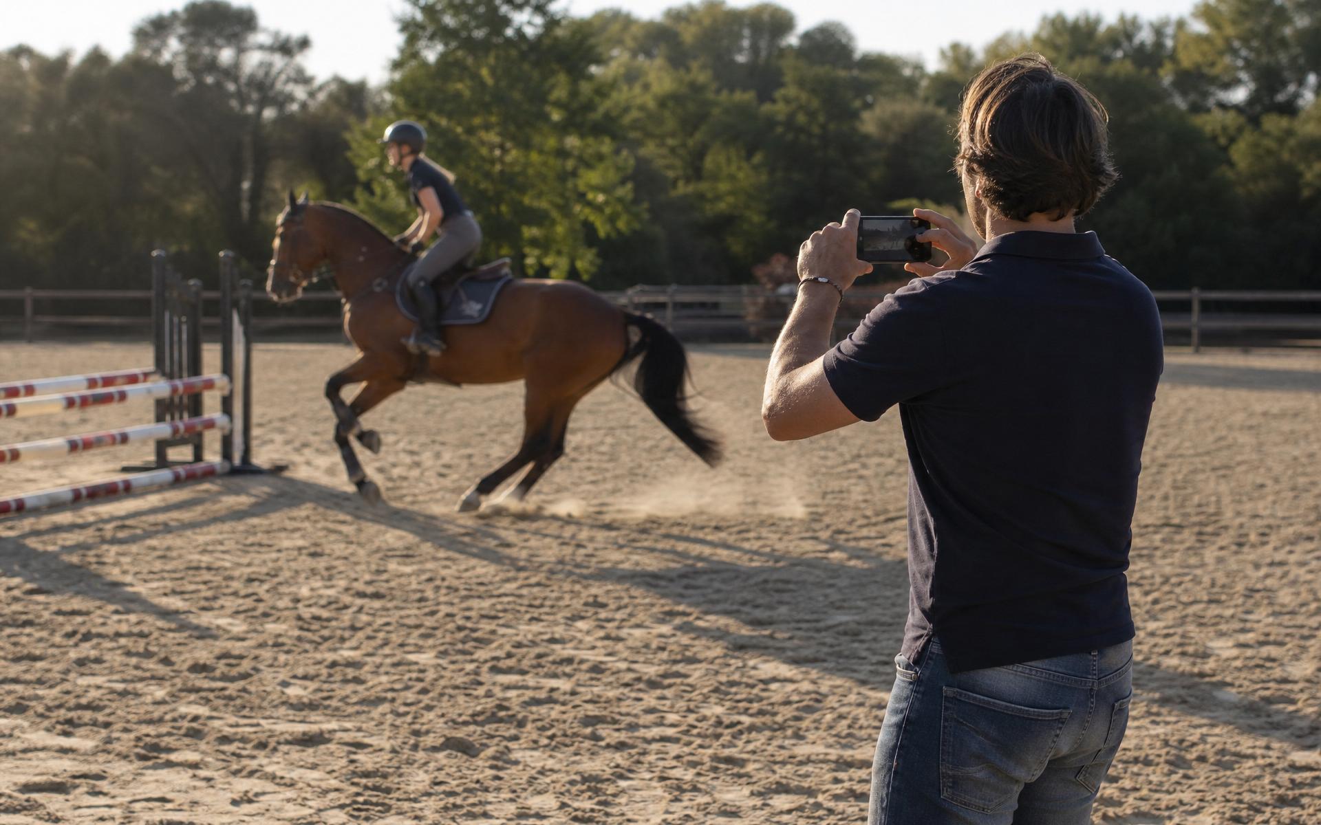Cavalière au travail en carrière filmée depuis le bord de la piste avec un smartphone